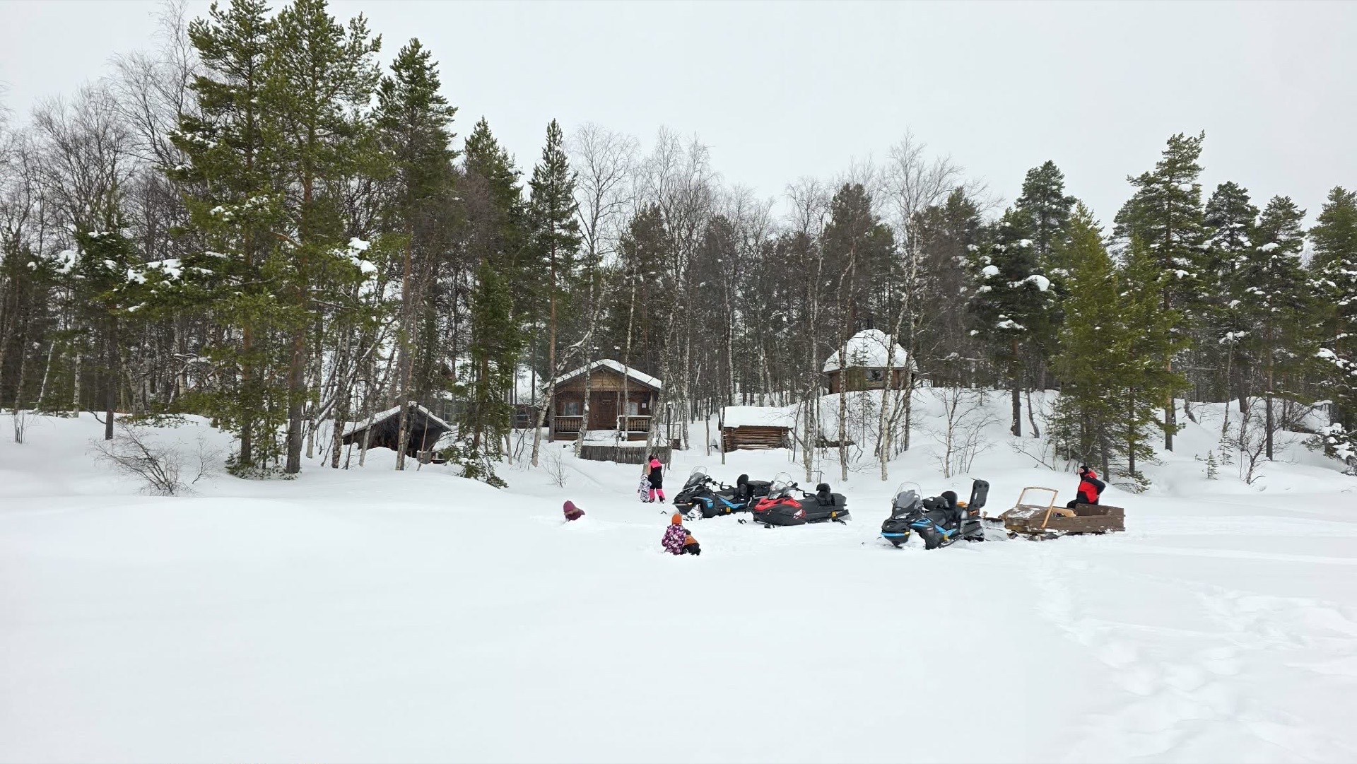 Snowmobiles and sled in front of the cabins on our private land